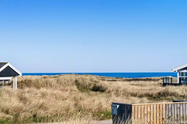 Two houses in a coastal area with dunes and sea view.