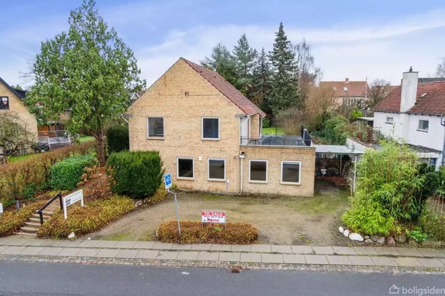 The house is a two-story brick building with a flat roof, located in a residential neighborhood.