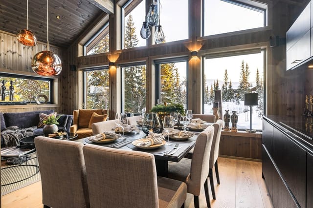 This modern cabin offers beautiful views of snow-covered trees through large windows, creating a bright and inviting atmosphere.