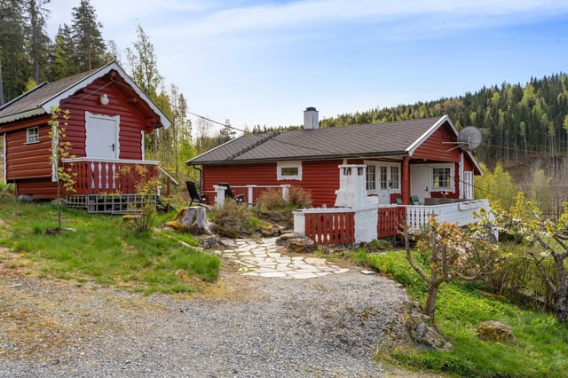 Welcome to Bottenvika 21 - Red cabin with terrace and a small outbuilding. Gravel driveway, stone-paved walkway, and surrounded by forest.