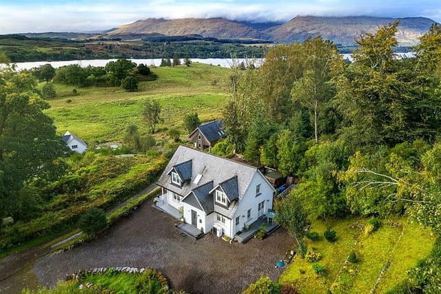 Front view of Taigh Geal with loch and mountain backdrop